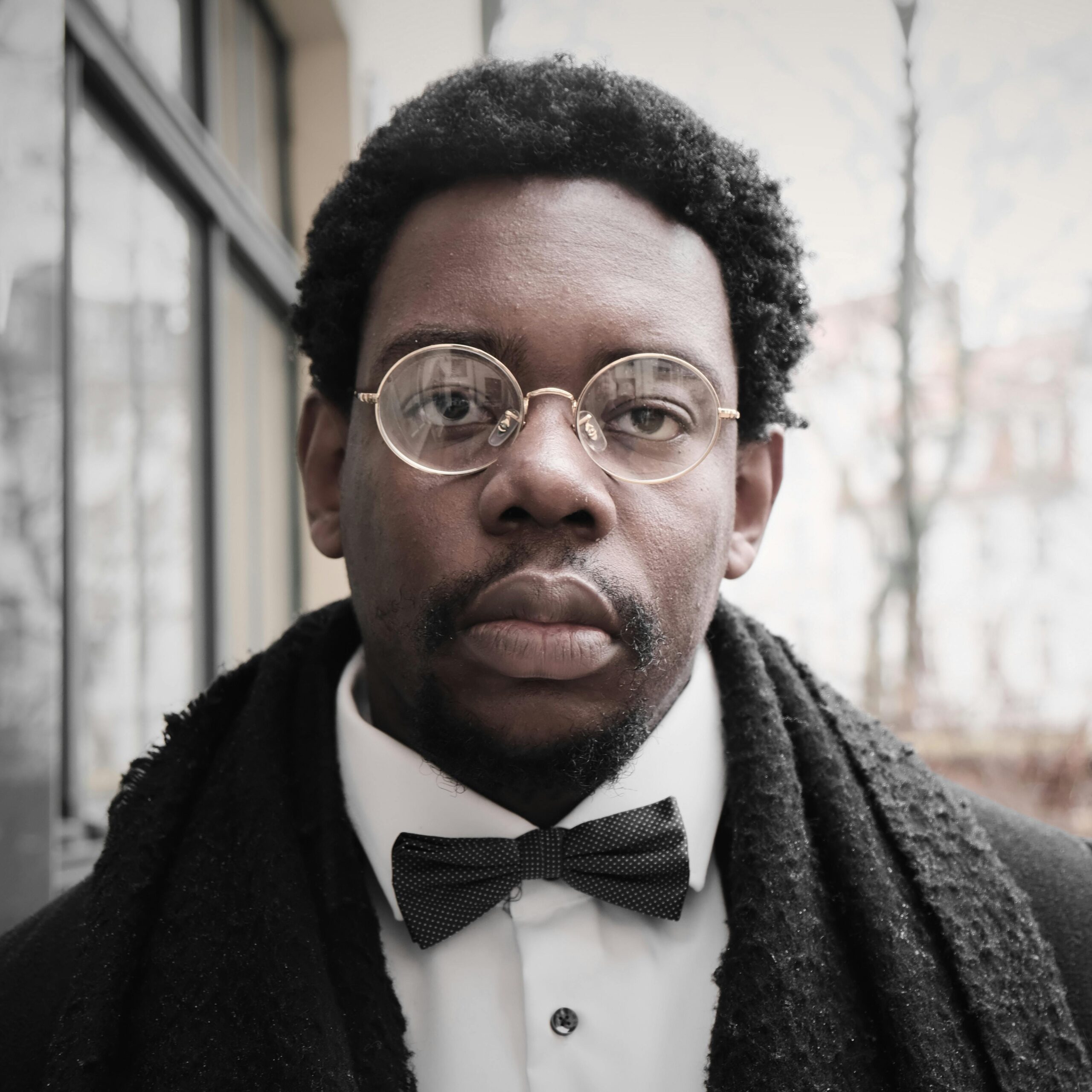 Home Sophisticated portrait of a man wearing a bow tie and glasses, exuding elegance.